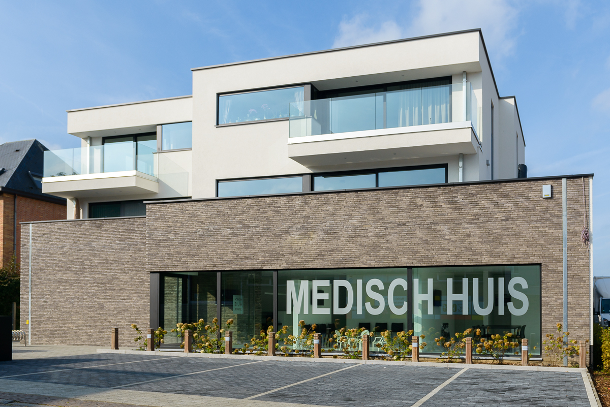 De verscheidenheid aan volumes zorgen voor een dynamische look en feel van het gebouw Voorkant moderne nieuwbouw voor medisch centrum in Ternat